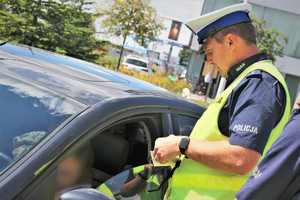 Zdjęcie przedstawia policjantka przeprowadzającego kontrolę drogową