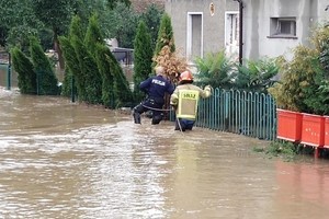 Zdjęcia przedstawiają policjanta przemieszczającego się po zalanej ulicy