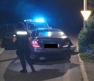 policjantka stojąca nocą koło auta na skrzyżowaniu