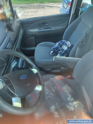Wnętrze pojazdu zatrzymanego mężczyzny, a w tle oznakowany radiowóz