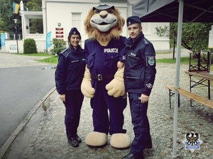 policjant i policjantka w umundurowaniu służbowym stoją na ulicy razem z maskotka dolnośląskiej policji - komisarzem lwem