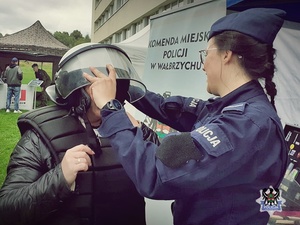 Policjantka przymierza kask policyjny innej osobie w trakcie targów pracy