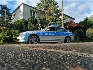 Policjant przy oznakowanym radiowozie