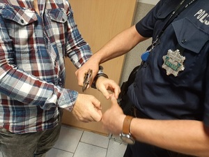 Policjant zakładający kajdanki na ręce zatrzymanego