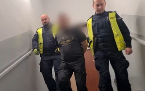 policjanci prowadzą zatrzymanego mężczyznę że schodów