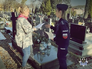 Policjantka rozdaje ulotki na cmentarzu i zawiesza informacje na tablicy ogłoszeń
