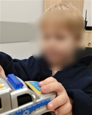 Zdjęcie przedstawia chłopca bawiącego się zabawkami