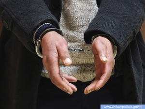Na zdjęciu widoczne są męskie ręce z założonymi kajdankami.