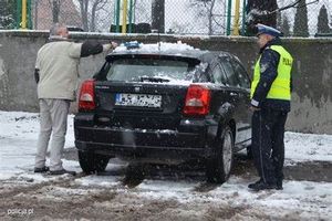 Mężczyzna odśnieżający samochód wraz z policjantem