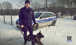Policjant z psem służbowym na tle radiowozu