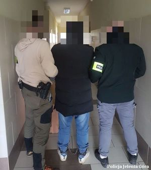 policjanci nie umundurowani stoją z zatrzymanym mężczyzną