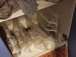 wnętrze szafy, w środku stojące w zawiniętych workach foliowych pojemniki, obok butelka z przezroczystym płynem