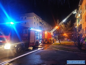 Na zdjęciu dwa wozy strażackie gaszące pożar w bloku.