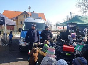 Na zdjęciu dwaj policjanci rozmawiają z dziećmi.