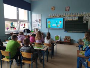 Na zdjęciu dzieci w klasie, siedzący w ławkach i oglądający film profilaktyczny.