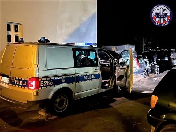 Zdjęcie zrobione nocą, radiowóz policyjny w nim policjantka i przed radiowozem zatrzymany samochód osobowy.