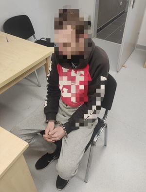 Zdjęcie zatrzymanego mężczyzny siedzącego w kajdankach.