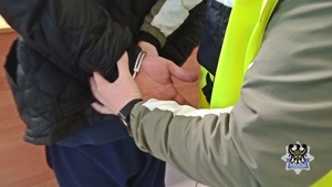 Na zdjęciu policjant zakładający kajdanki mężczyźnie.