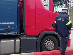 policjant przy samochodzie ciężarowym na dworze przy drodze