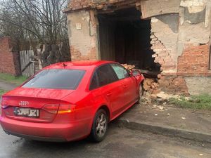 Na zdjęciu tył czerwonego samochodu osobowego po zderzeniu w ścianę budynku.