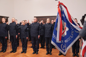 Na zdjęciu nowo przyjęci policjanci z uniesionymi dwoma palcami ku górze mówią rotę ślubowania.