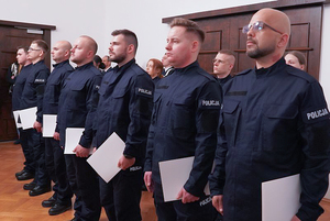 Na zdjęciu nowo przyjęci policjanci trzymający w rękach akty ślubowania.