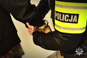 Na zdjęciu policjant zakłada kajdanki na ręce zatrzymanego.
