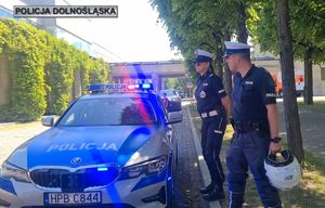 Policjant na dworze przy oznakowanym radiowozie