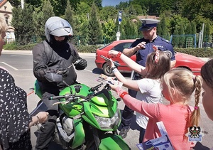 Policjant z dwiema dziewczynkami kontrolują kierowcę motoru.