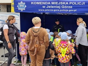 Na zdjęciu policjantka rozmawia z dziećmi i opiekunkami dzieci.