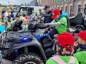 Na zdjęciu dzieci siedzą na policyjnych quadach i motorach podczas festynu.