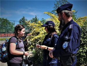 Na zdjęciu policjant  i policjantka  rozmawiają z dziewczynką