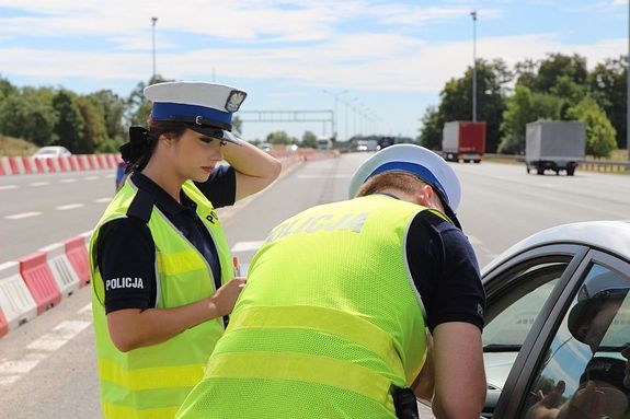 Na zdjęciu policjantka i policjant kontrolujący kierowcę pojazdu osobowego.