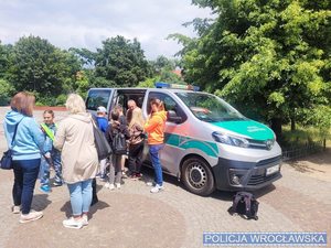 Ludzie stoją obok busa straży granicznej