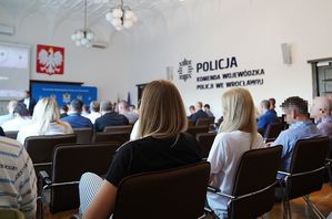 Policjanci siedzą na krzesłach w dużej sali