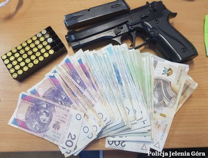 Banknoty, amunicja i pistolet leżące na stole.