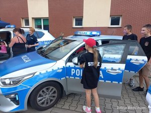 Dzieci stojące przy radiowozie policyjnym.