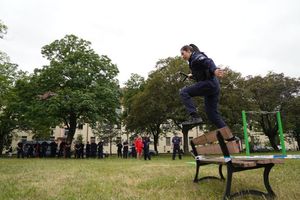 Policjantka przeskakuje przez ławkę.