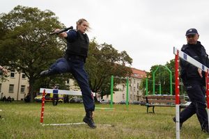 Policjantka skacze przez płotek.