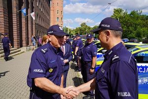 policjanci stojący na dworze przy oznakowanych radiowozach