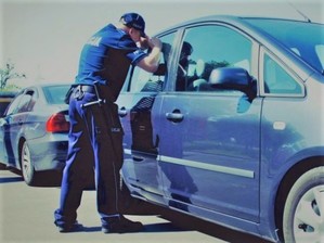 policjant zagladajacy przez okno do samochodu