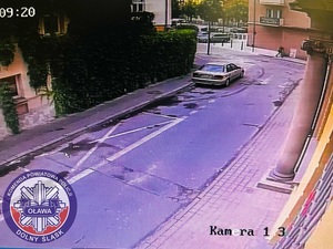 Zdjęcie z kamery na budynku przedstawiające samochód osobowy jadący ulicą.