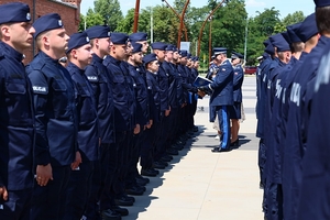 Komendant Wojewódzki Policji we Wrocławiu nadinspektor Dariusz Wesołowski przekazuje dyplomy poszczególnym nowo przyjętym policjantom stojącym w dwuszeregu.