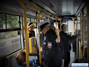Policjantka rozmawiająca w autobusie MPK z pasażerem siedzącym na siedzeniu.