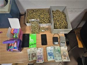 Marihuana, telefony komórkowe, pieniądze i wagi elektroniczne leżące na stole