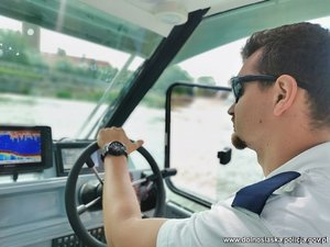 Policjant steruje łodzią motorową