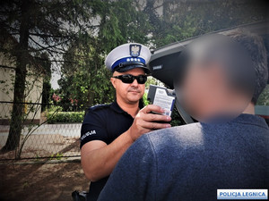 Policjant alkomatem sprawdza stan trzeźwości mężczyzny.