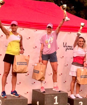 Trzy kobiety z pucharami stojące na podium