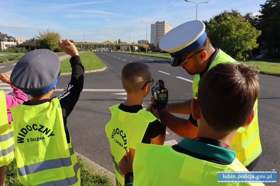 Policjant pokazuje dzieciom jak działa urządzenie do pomiaru prędkości.