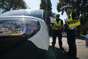 Dwaj policjanci kontrolują samochód osobowy.
